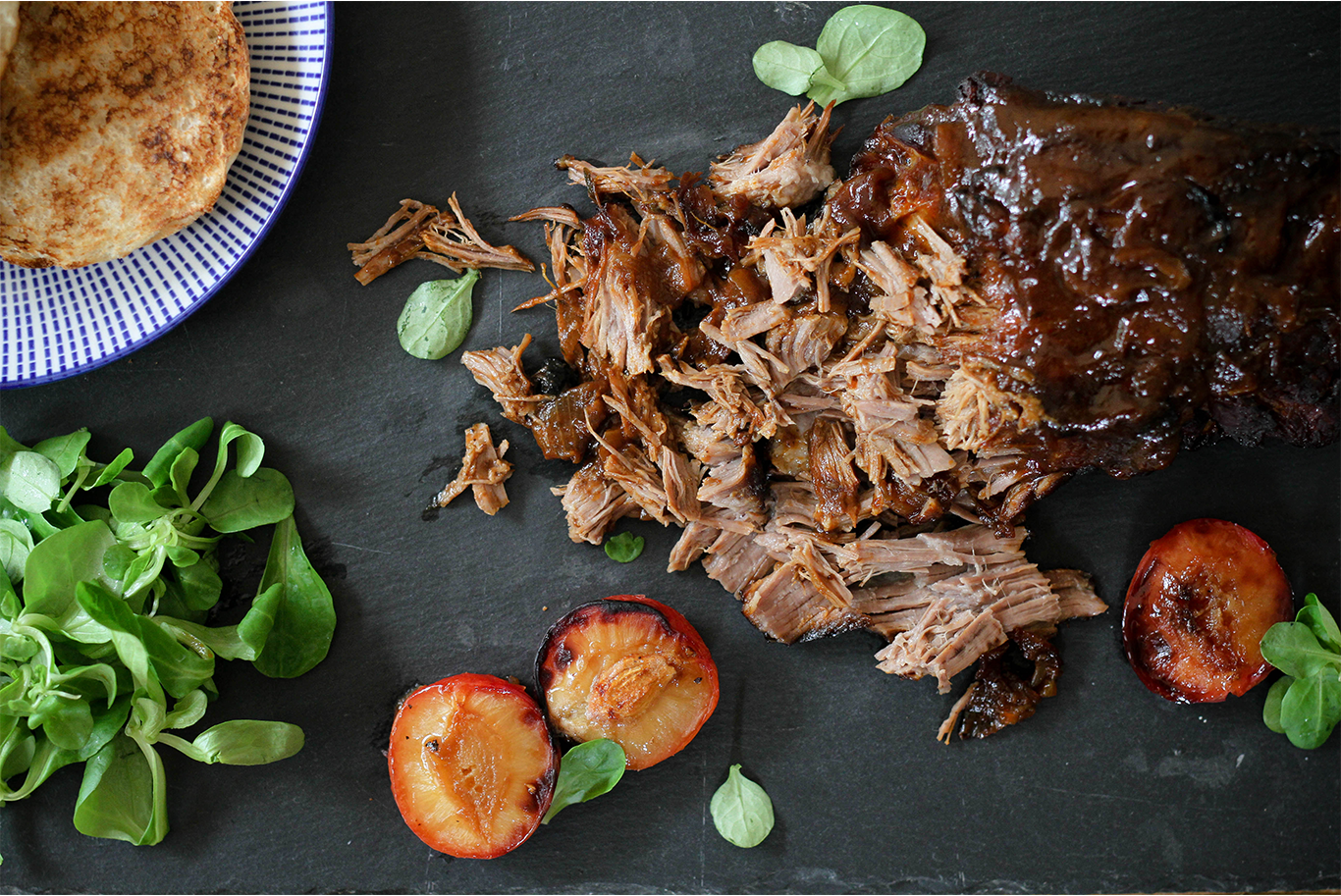 pulled pork on a black slate serving slab with lambs lettuce, toasted buns and caramelised plums